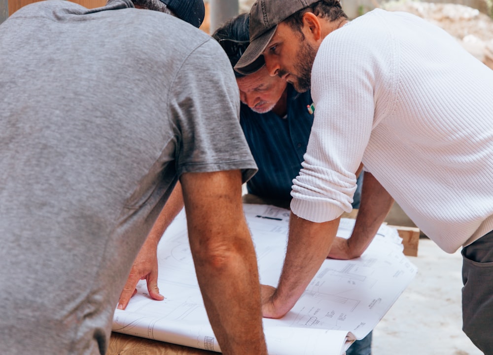 Three tradespeople reviewing plans at a worksite